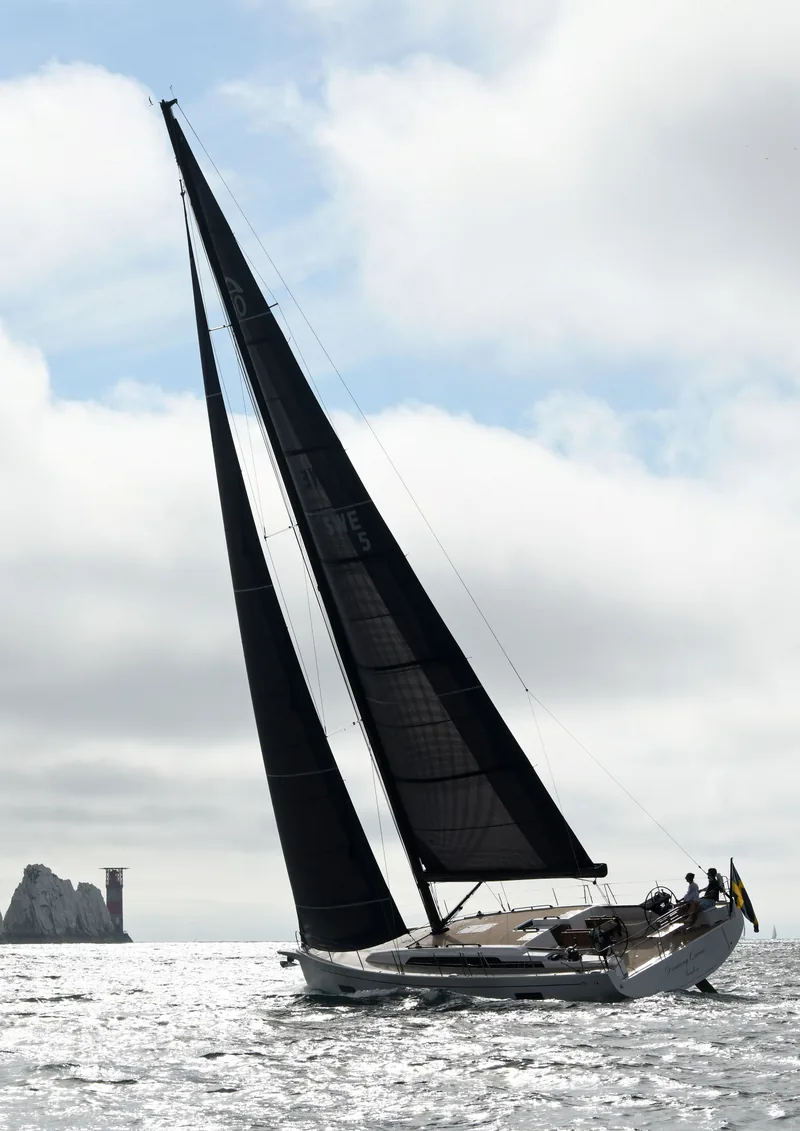 Arcona 50 Dancing Queen under black sails at the rocks